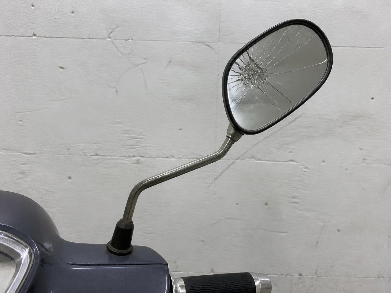 Vänster backspegel med krossat spegelglas och böjt spegelfäste.